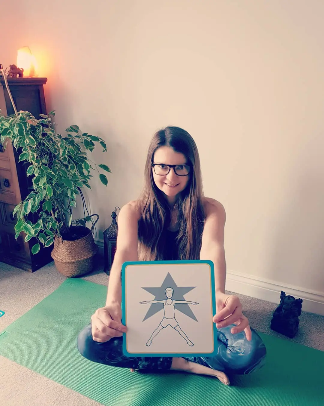 Edy holding an instructional card showing a yoga pose